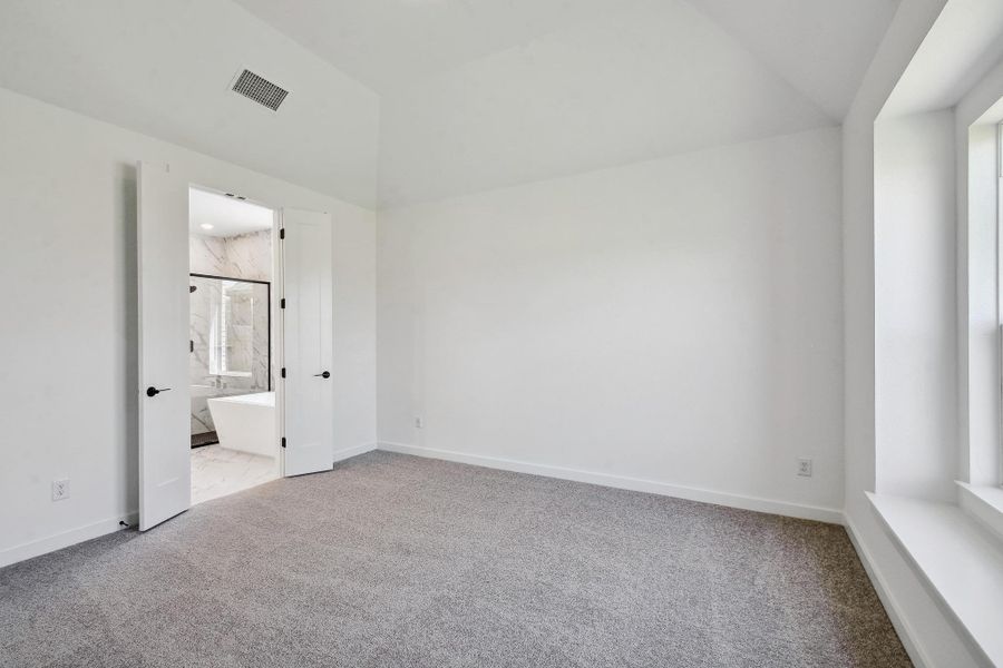 Unfurnished bedroom featuring carpet, vaulted ceiling, and ensuite bathroom
