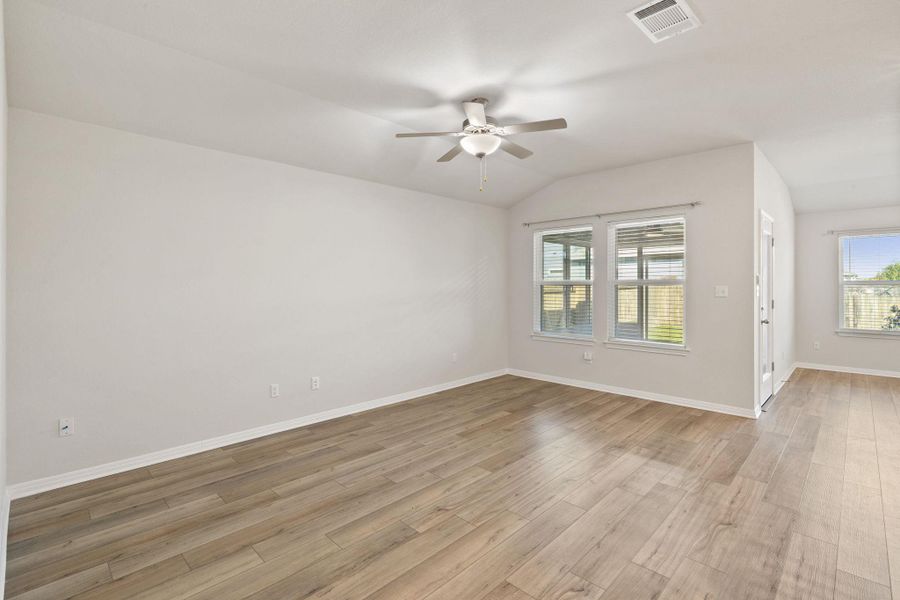 Unfurnished room with light wood-type flooring, lofted ceiling, a ceiling fan, and healthy amount of natural light Unfurnished room with light wood-type flooring, lofted ceiling, a ceiling fan, and healthy amount of natural light