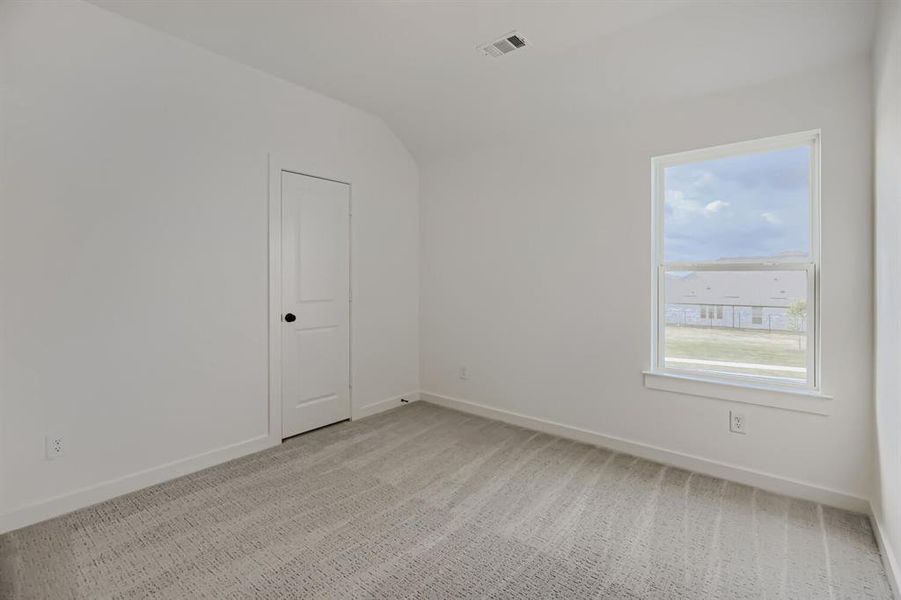 Unfurnished room featuring light colored carpet and lofted ceiling