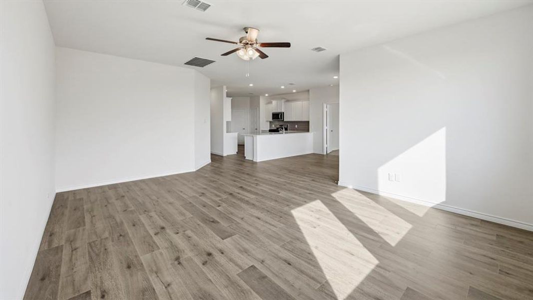 Expansive open-concept living area featuring wood-finish flooring and a ceiling fan Expansive open-concept living area featuring wood-finish flooring and a ceiling fan
