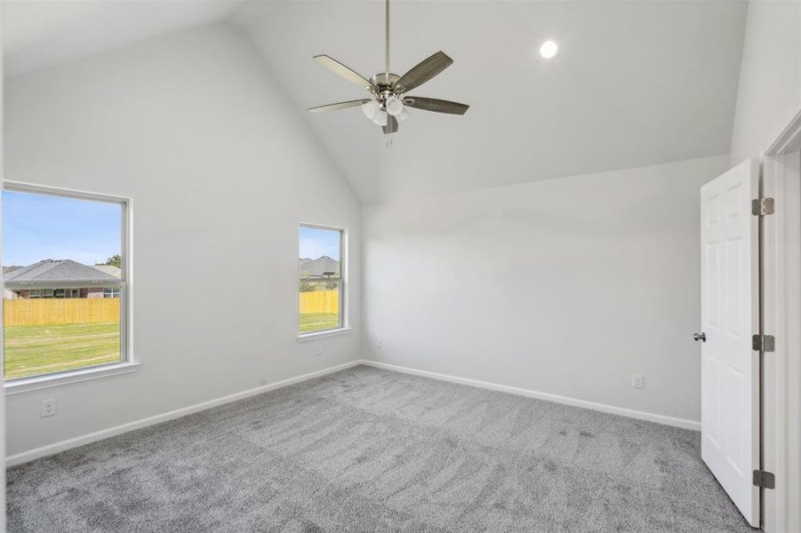 Empty room featuring ceiling fan, light colored carpet, and high vaulted ceiling