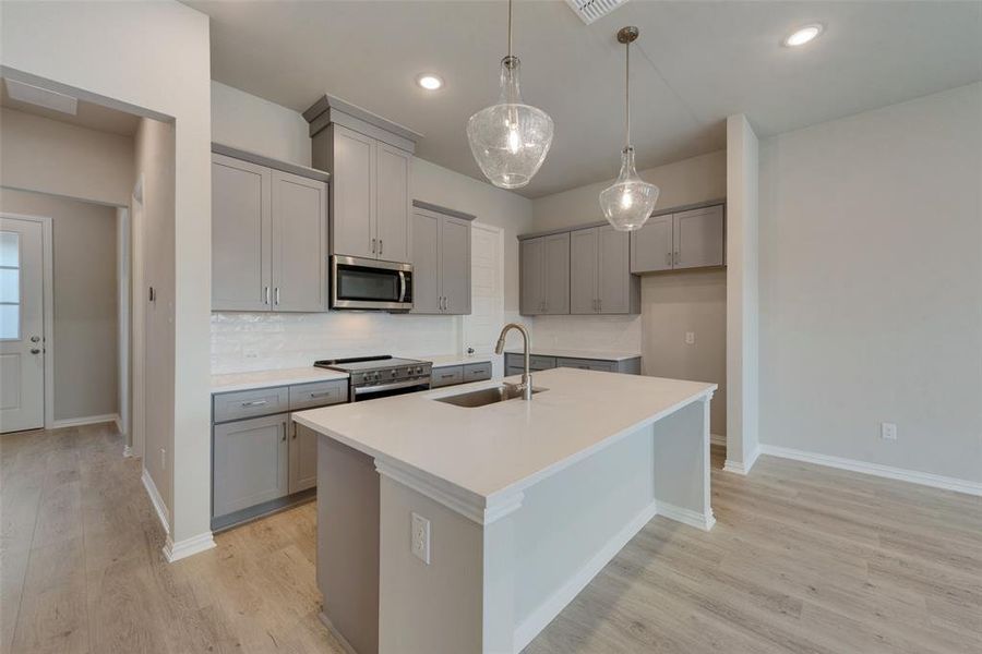 Kitchen with sink, tasteful backsplash, stainless steel appliances, and light hardwood / wood-style floors