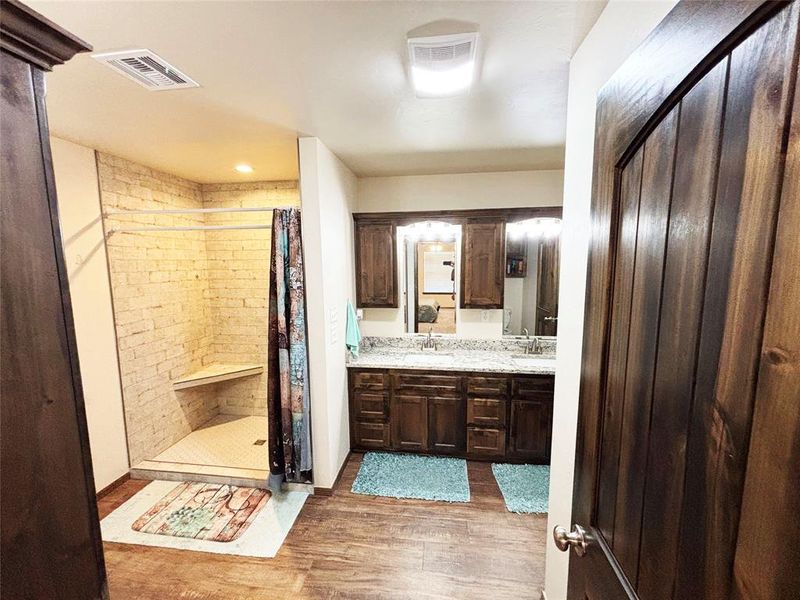 Bathroom with double vanity, light wood finished floors, and a stall shower Bathroom with double vanity, light wood finished floors, and a stall shower