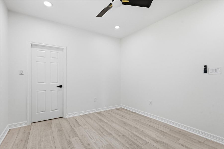 Second floor bedroom with ceiling fan, white walls, and light wood look floors.