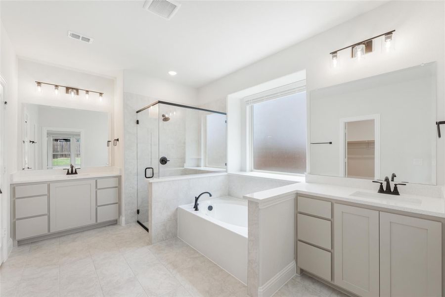 Master bathroom with dual vanities, soaking tub, and glass walk-in shower with tile surround Master bathroom with dual vanities, soaking tub, and glass walk-in shower with tile surround