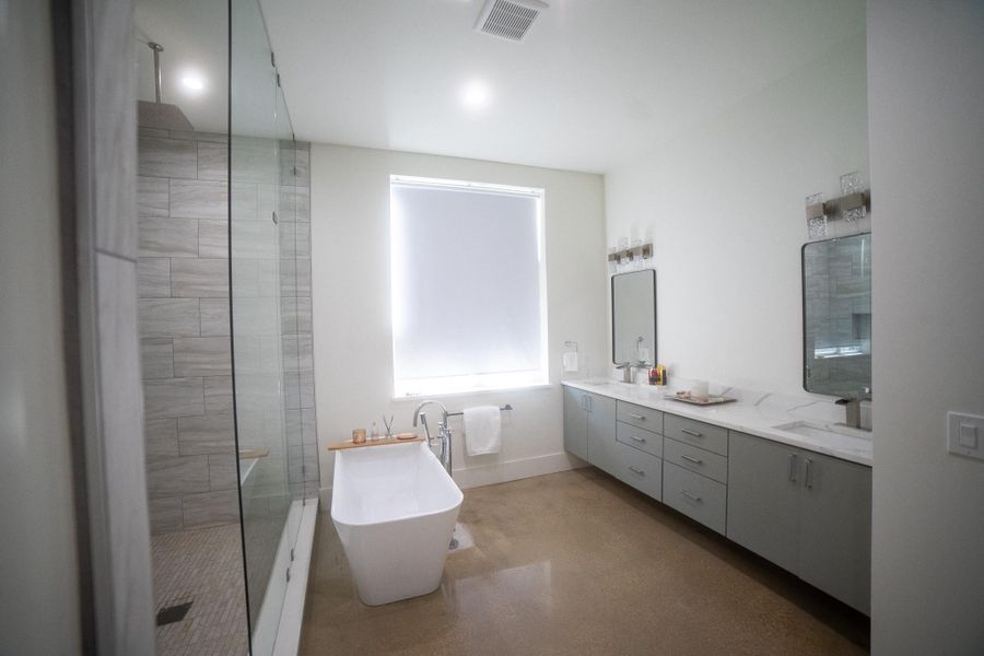 Escape to a private spa-like sanctuary featuring a glass-enclosed walk-in shower and a deep freestanding soaking tub. The sleek dual-sink vanity offers generous counter space, while a large window bathes the entire room in soothing natural light for a bright, airy start to your day