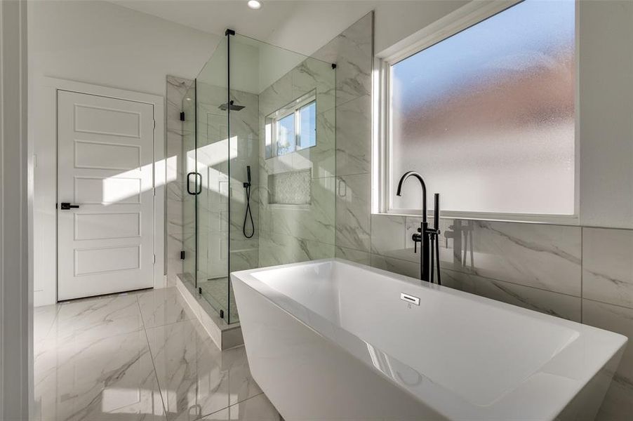 Full bath with light marble finish floors, a freestanding tub, a marble finish shower, tile walls, and recessed lighting