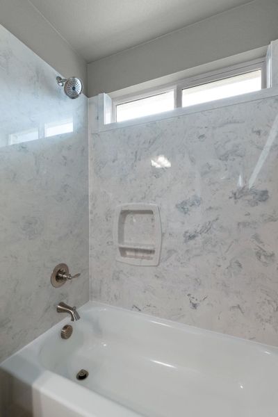 Bathtub and shower combination with window for natural light.