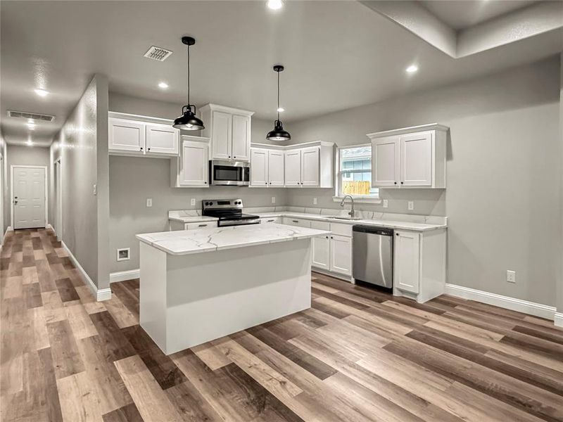 Kitchen featuring white cabinetry, a kitchen island, appliances with stainless steel finishes, pendant lighting, and recessed lighting