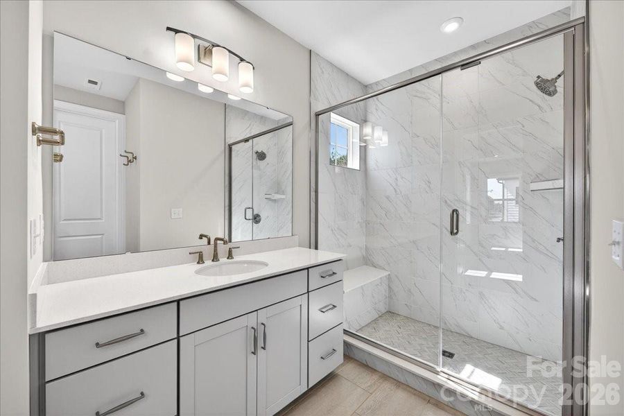 Dual vanity primary bathroom with tiled walk-in shower Dual vanity primary bathroom with tiled walk-in shower
