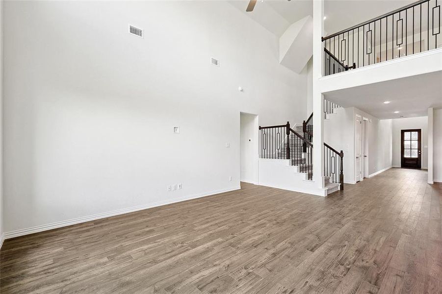 Unfurnished living room with a towering ceiling, hardwood / wood-style floors, and ceiling fan