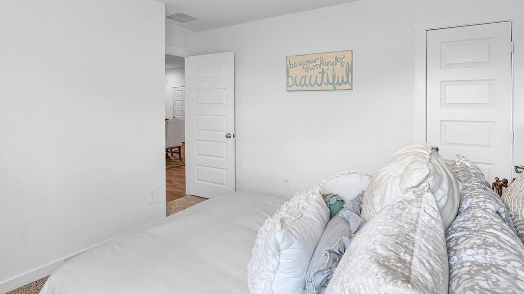 Guest bedroom featuring neutral-toned walls, carpeted flooring, and a separate closet.