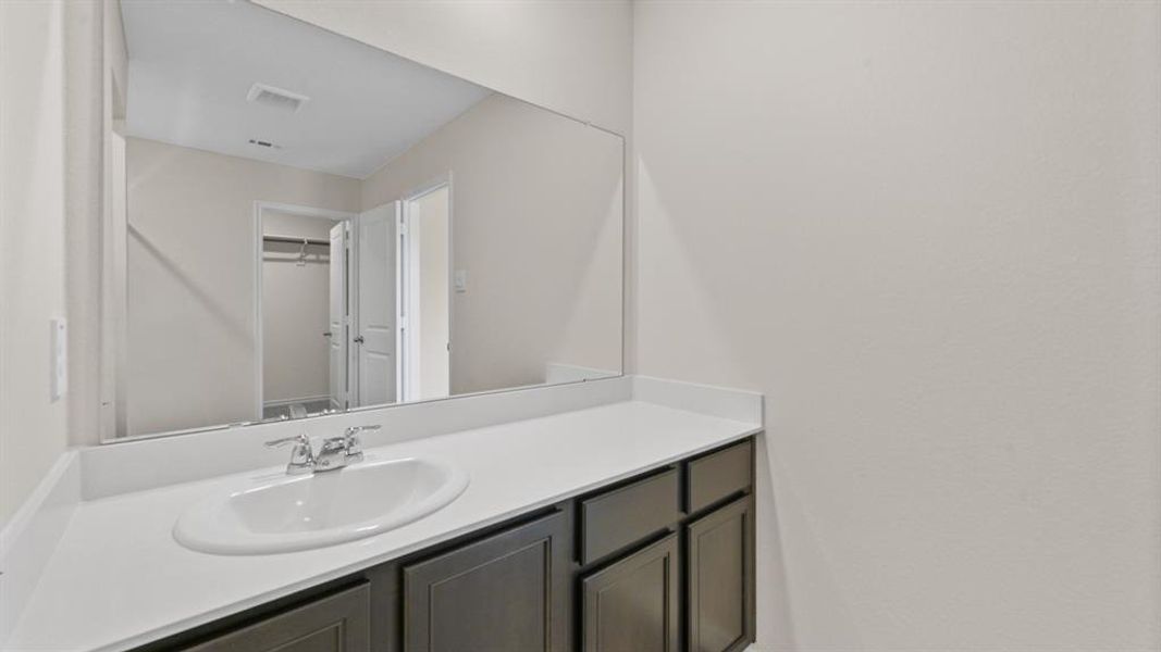 Bathroom vanity featuring a single basin sink, chrome faucet, and expansive wall-mounted mirror Bathroom vanity featuring a single basin sink, chrome faucet, and expansive wall-mounted mirror