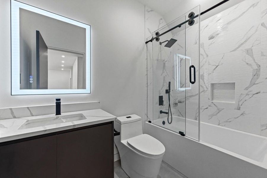 Bathroom featuring vanity and shower / bath combination with glass door