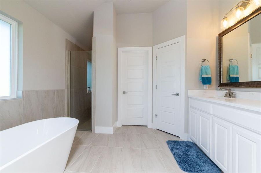 Full bathroom with a stall shower, a soaking tub, vanity, and light tile patterned floors