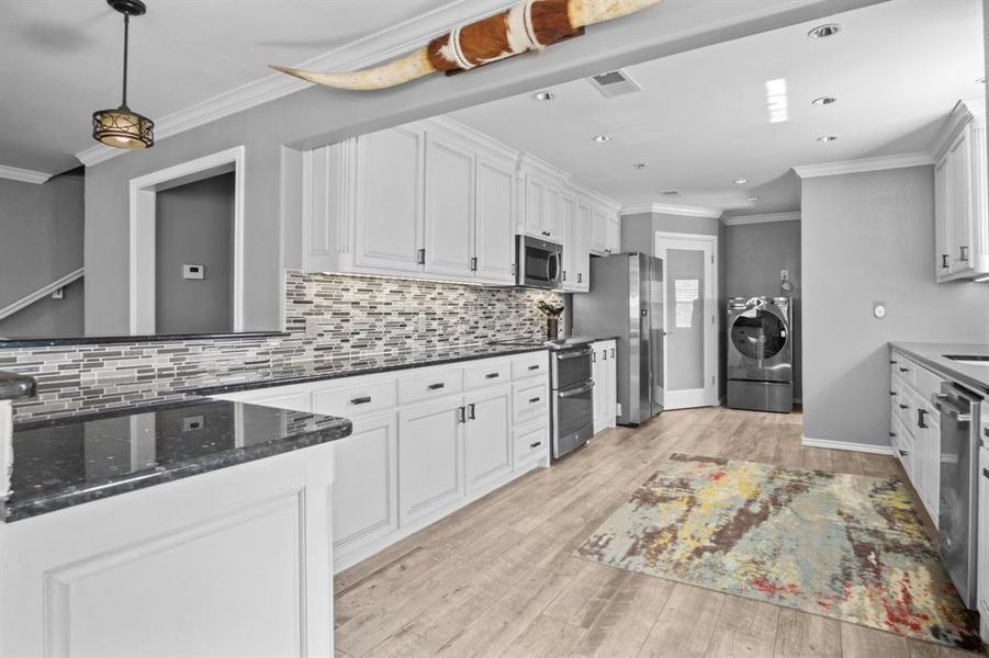 Kitchen featuring crown molding, appliances with stainless steel finishes, and white cabinetry