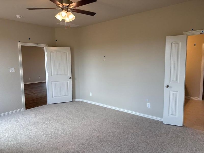 Carpeted room with neutral wall tones and a ceiling fan with integrated lighting