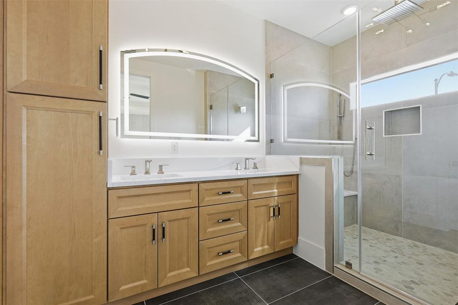 The Primary bath is equipped with a dual-sink vanity, matte black hardware, and an LED-backlit arched mirror.