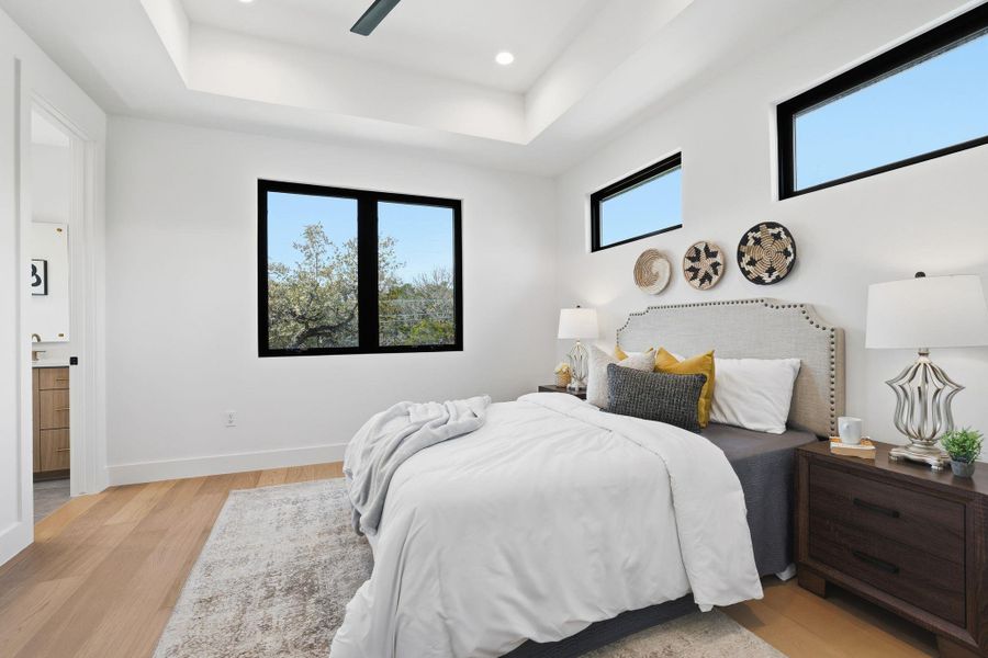 Bedroom featuring light wood-type flooring, a raised ceiling, ceiling fan, and recessed lighting