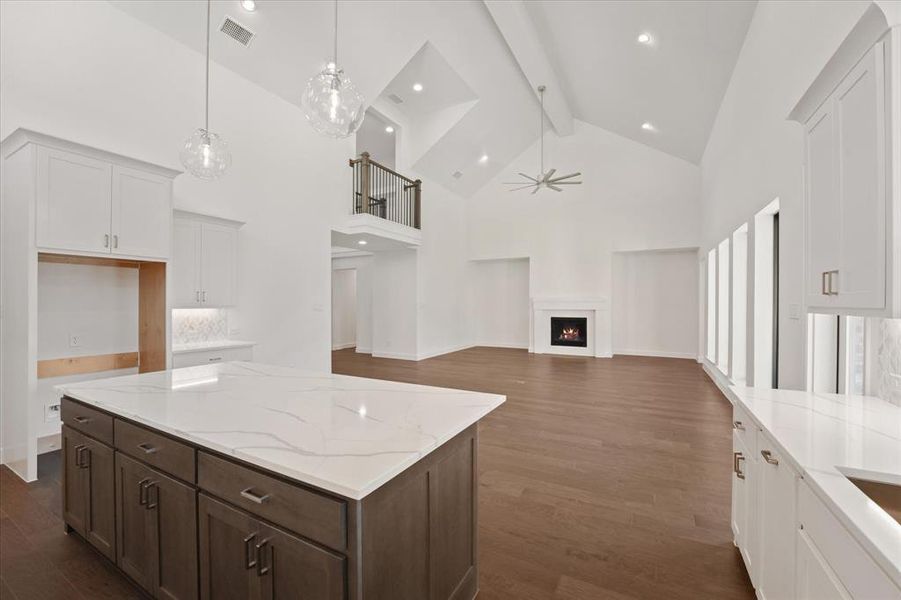 Kitchen featuring beam ceiling, high vaulted ceiling, a ceiling fan, white cabinets, and dark wood-style flooring