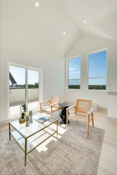 Living room featuring a wealth of natural light, high vaulted ceiling, and light wood-type flooring