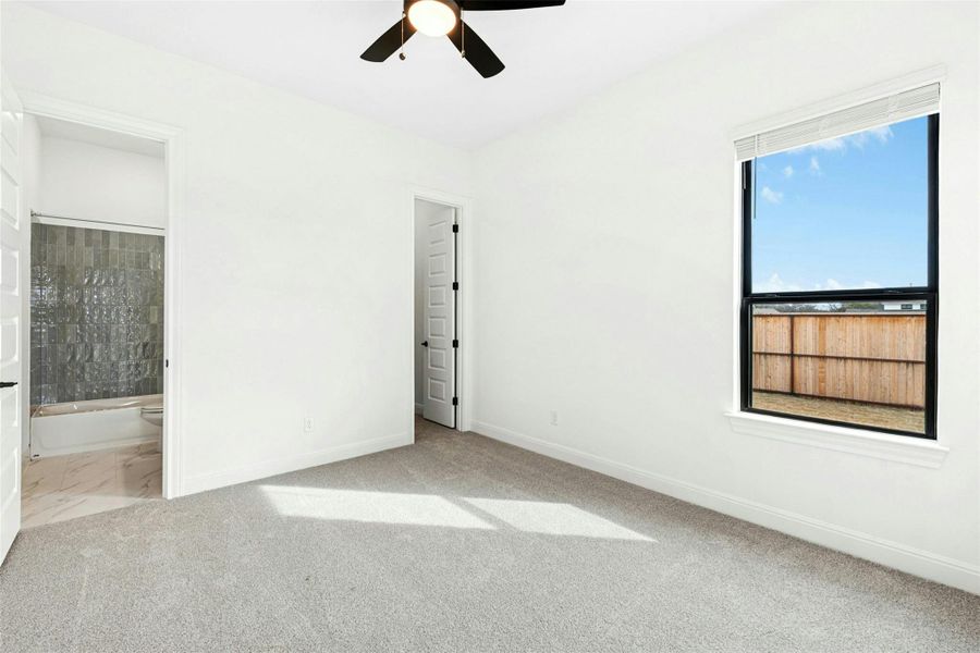 Unfurnished bedroom with light colored carpet, ceiling fan, and ensuite bathroom