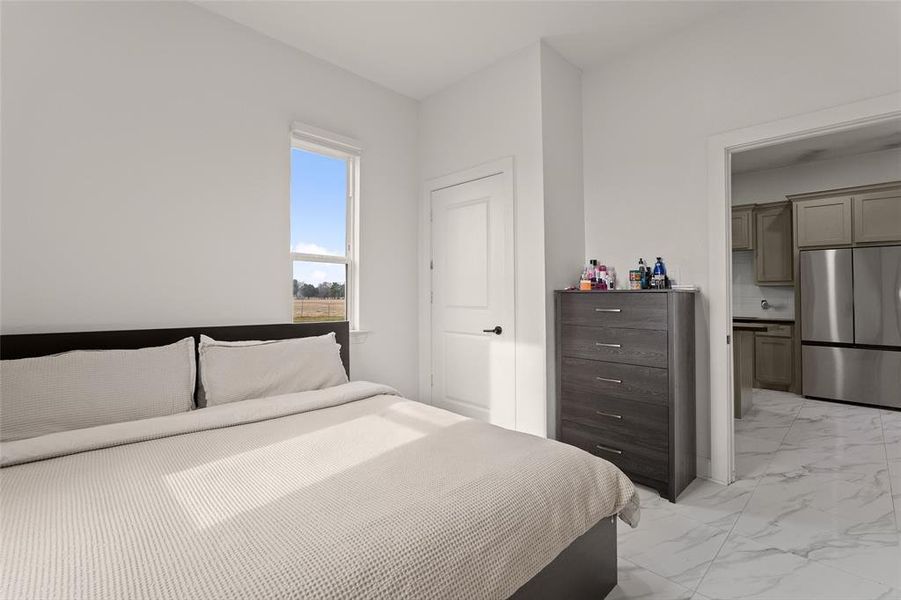 Bright room featuring a window overlooking an open field, white walls, and white marble-look tile flooring Bright room featuring a window overlooking an open field, white walls, and white marble-look tile flooring