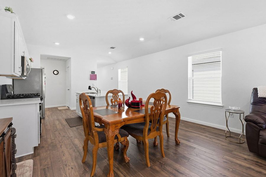 Dining space with vaulted ceiling, dark wood finished floors, and recessed lighting