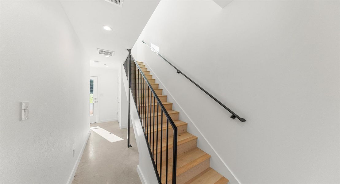 A light-filled stairwell connects the home's three levels, with clean lines and natural light that make everyday movement feel effortless. Model No. 104 Shown.