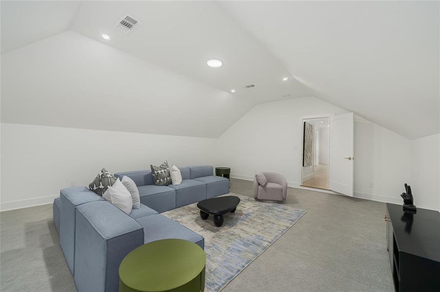 Spacious living area featuring a vaulted ceiling with recessed lighting, light-colored carpeting, and a white interior door