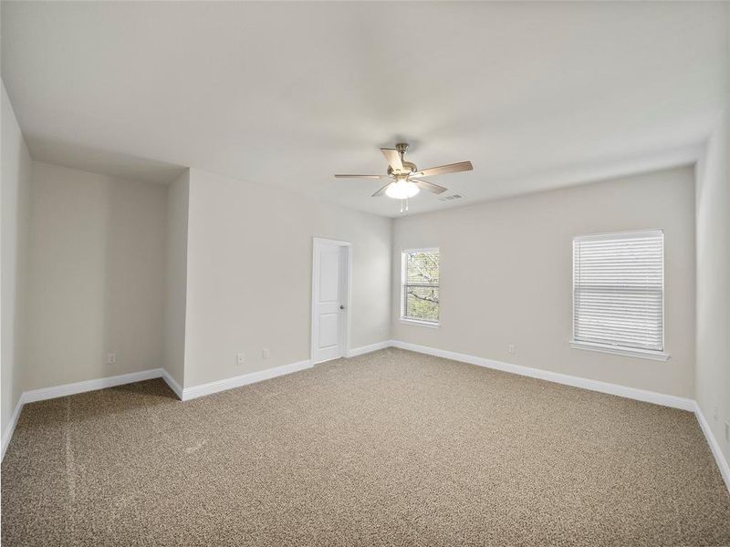 Spare room featuring ceiling fan, carpet flooring, visible vents, and baseboards