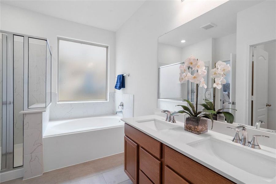 This primary bathroom is definitely move-in ready! Featuring an oversized framed walk-in shower with tile surround, separate garden tub for soaking after a long day with custom tile detailing, stained cabinets with light countertops, spacious walk-in closet with shelving, high ceilings, neutral paint, sleek and modern finishes.