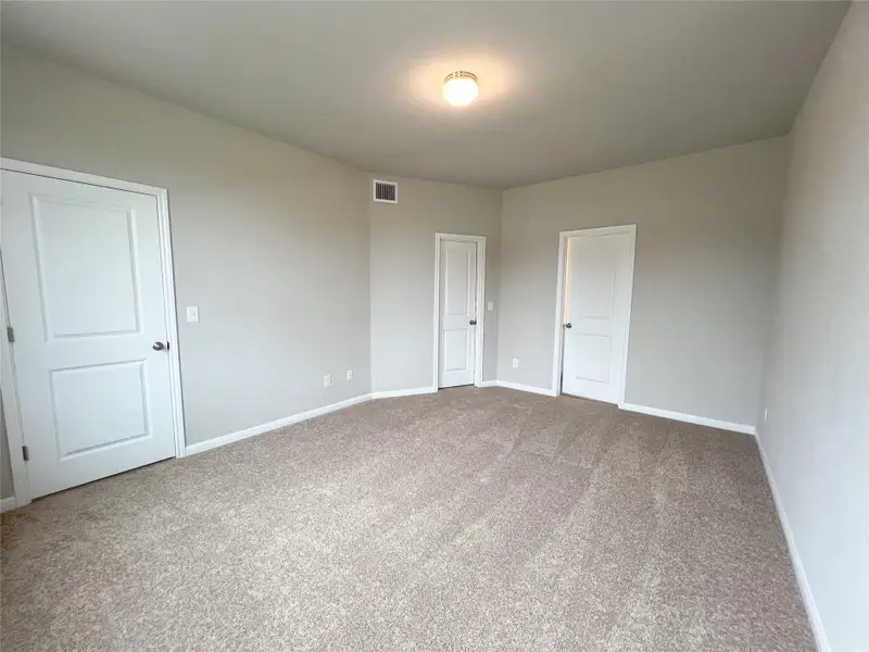 Unfurnished bedroom with light carpet and baseboards
