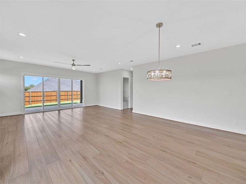 room featuring ceiling fan with notable chandelier and light wood-type flooring