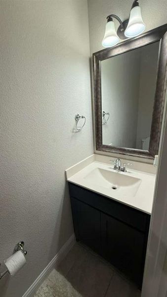 Bathroom featuring a textured wall, vanity, and dark tile patterned floors