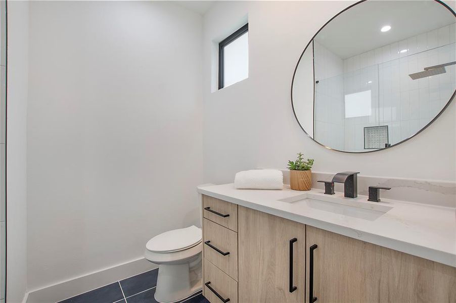 Bathroom featuring tile patterned flooring, walk in shower, toilet, and vanity