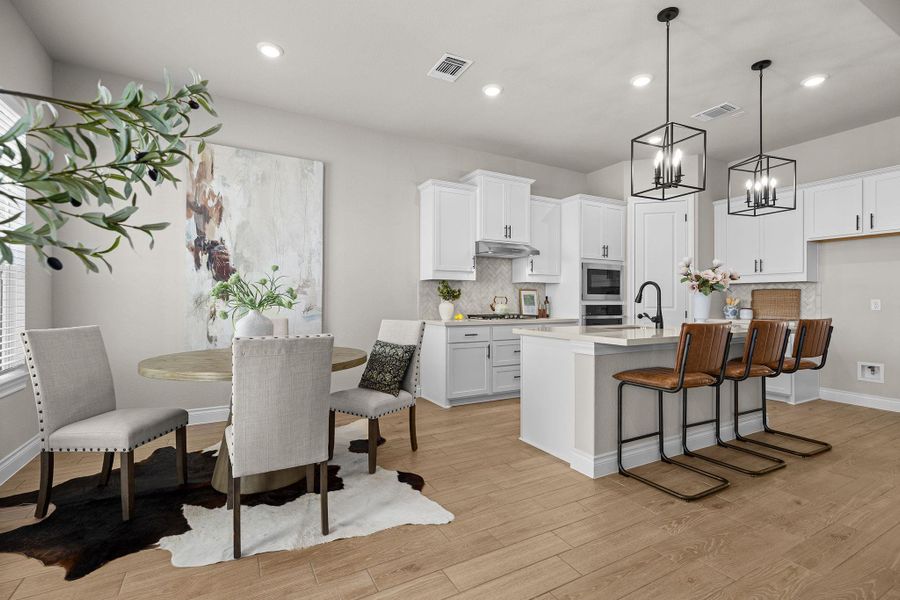 Kitchen featuring a breakfast bar, tasteful backsplash, an island with sink, pendant lighting, and white cabinets