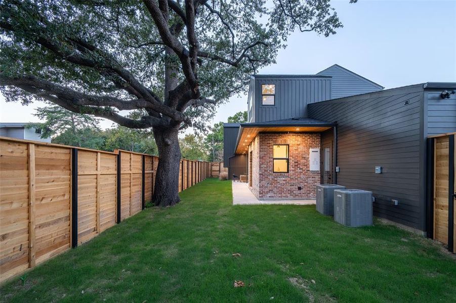 Rear view of property with central air condition unit and a lawn