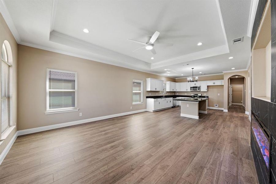 Kitchen featuring dark countertops, a raised ceiling, stainless steel microwave, and visible vents