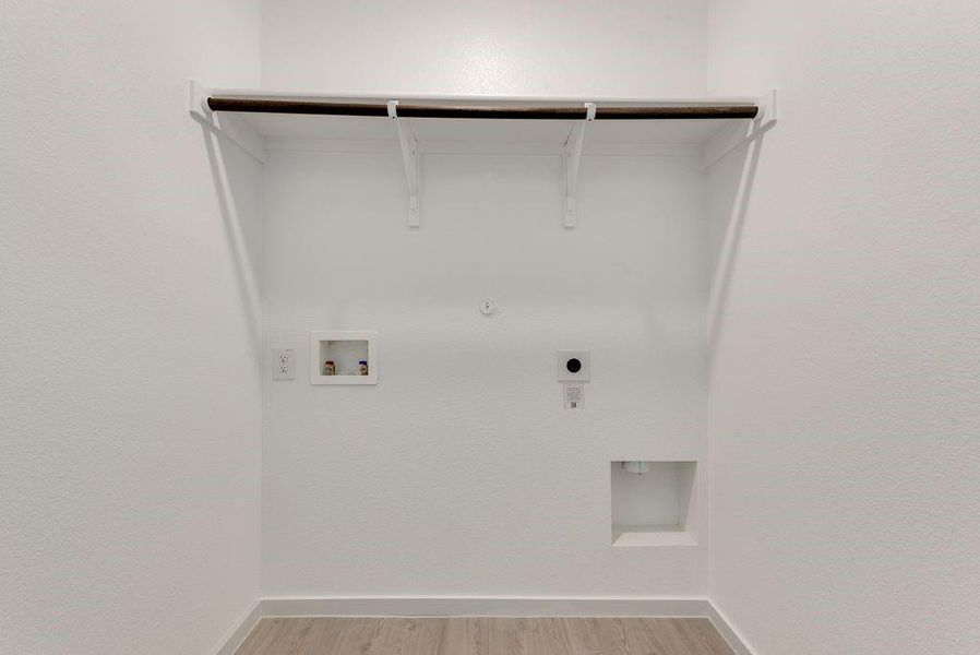 Washroom with hookup for a gas dryer, washer hookup, hookup for an electric dryer, and light wood-type flooring