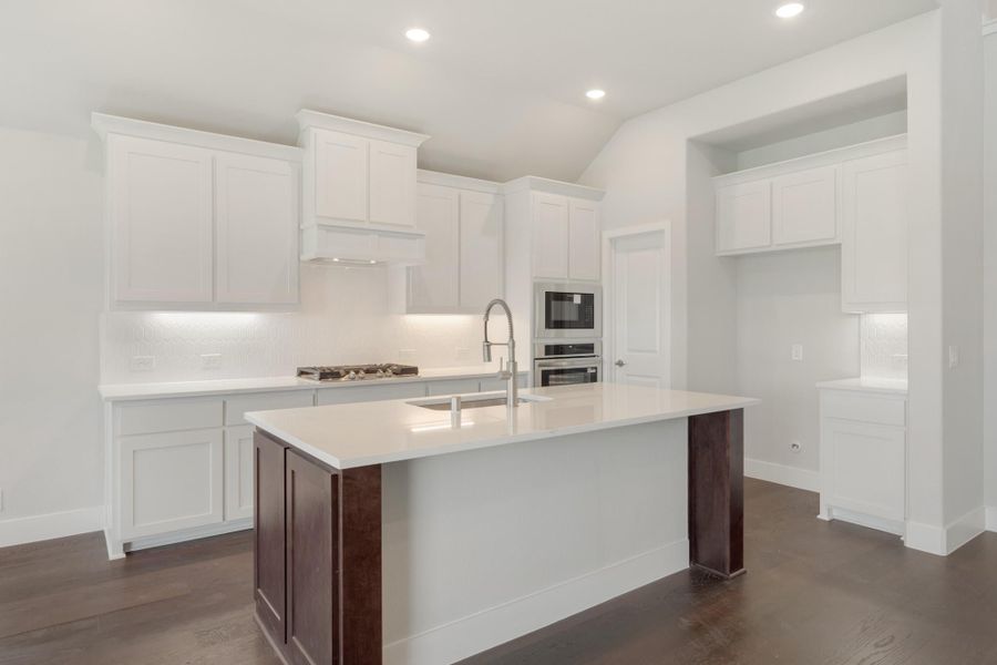 White kitchen with center island, dark wood base, white countertops, stainless appliances, and dark hardwood floors White kitchen with center island, dark wood base, white countertops, stainless appliances, and dark hardwood floors