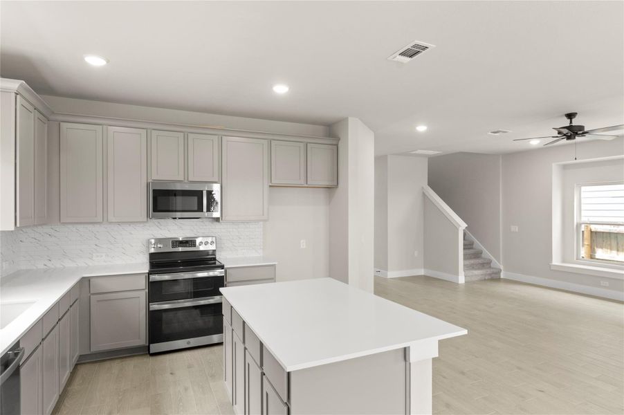 Kitchen with stainless steel appliances, gray cabinetry, backsplash, a center island, and recessed lighting Kitchen with stainless steel appliances, gray cabinetry, backsplash, a center island, and recessed lighting