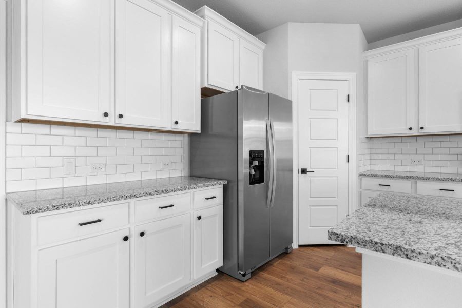 White cabinetry with black hardware, granite counters, and a full stainless steel refrigerator define this clean and modern kitchen. White cabinetry with black hardware, granite counters, and a full stainless steel refrigerator define this clean and modern kitchen.