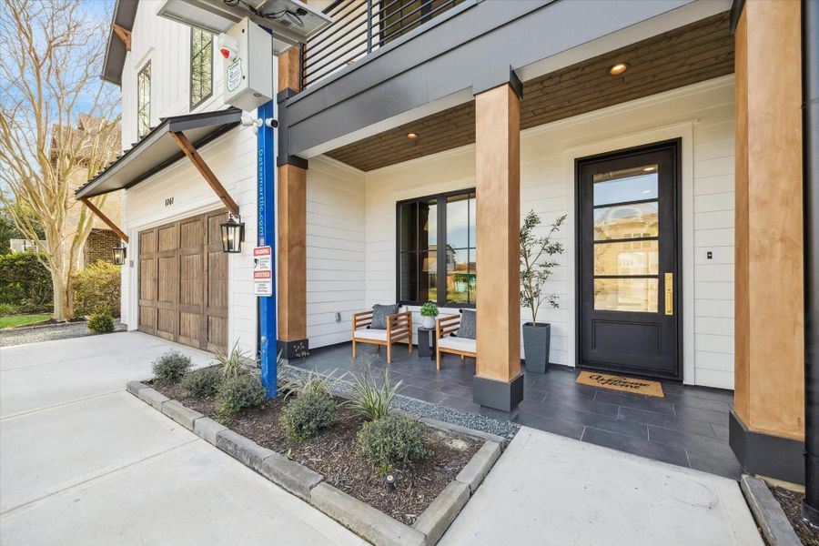 Offering a welcoming and spacious front porch. Features wooden accents and stylish black iron front door.