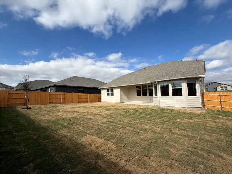 Rear view of house with a patio area, a fenced backyard, and roof with shingles