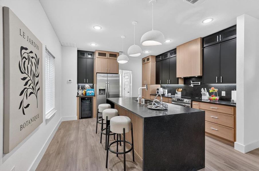 Gourmet kitchen featuring a large central island with seating, a stainless steel French door refrigerator, and a built-in beverage cooler