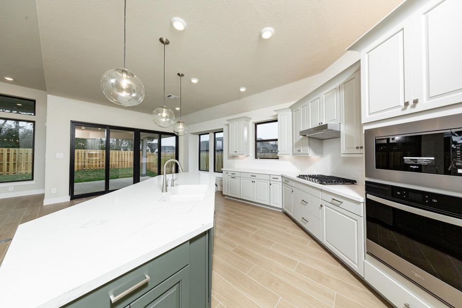 The kitchen includes Whirlpool stainless steel appliances: 30" gas cooktop, coordinating built-in stainless steel microwave, oven wall unit, and dishwasher suggesting a professional and polished space.