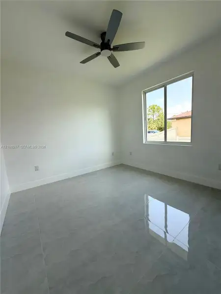 Neutral-toned polished tile flooring, crisp white walls, and a multi-blade matte black ceiling fan