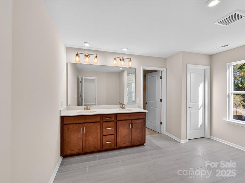 Primary En Suite Bath with Modern Wood-Toned Cabinetry and Dual Vanity.