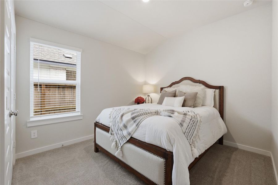 Cozy Guest bedroom with neutral tones, featuring a comfortable bed, plush carpeting, and a window providing natural light. Ideal for relaxation and rest.